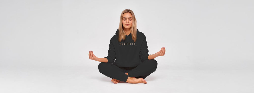 Woman meditating while wearing frequency-embedded affirmation T-shirt